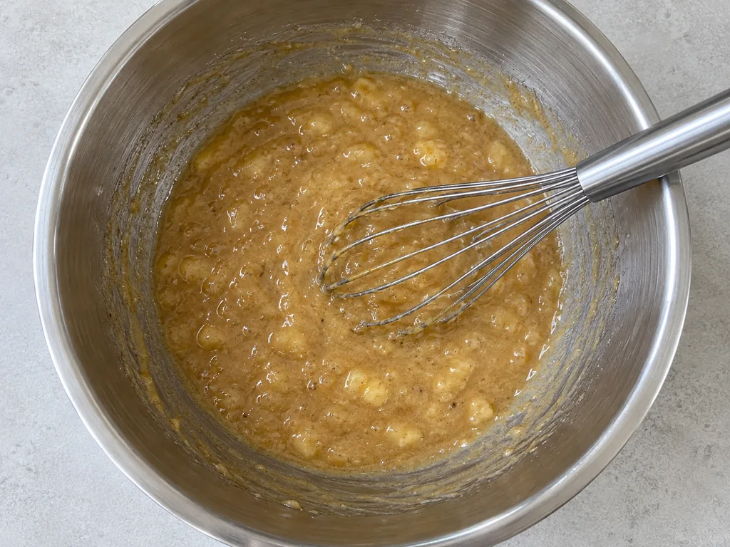 Whisk in the eggs. Whisk in the eggs one at a time, beating each until no yolk streaks remain and the base looks glossy.
