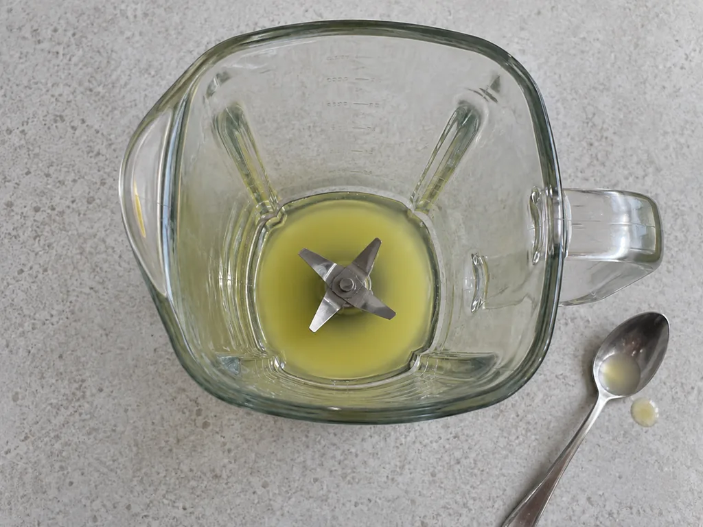 Smooth lemon and dissolved-sugar mixture in a stopped blender jar, with a tasting spoon beside it.