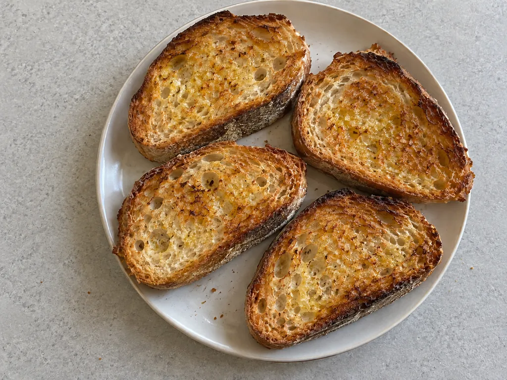 Four crisp golden slices of garlic toast on a plate.